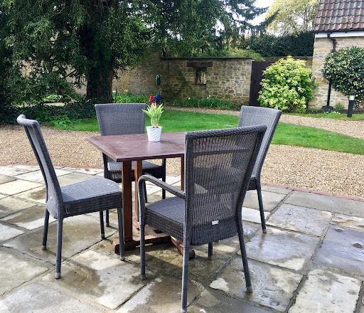 A cozy outdoor seating area with a table and chairs, set in a green garden.