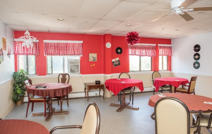 A cozy dining area with red walls and checkered window blinds.