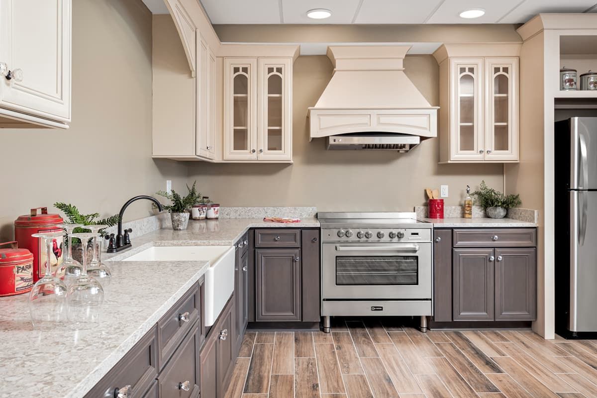 A modern kitchen with stylish cabinets, a large stove, and wooden flooring.