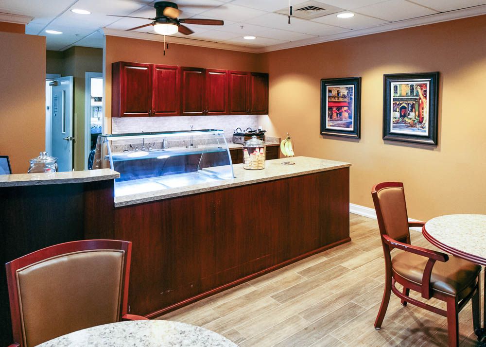 A cozy coffee shop interior featuring a wooden counter and seating area with art pieces on the walls.