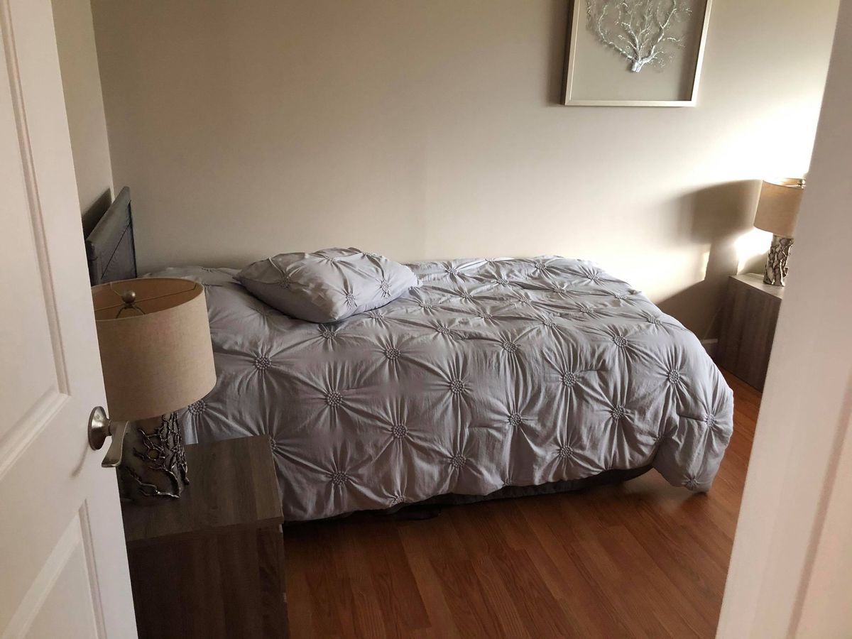 A cozy bedroom with neatly arranged bedding and a bedside lamp.