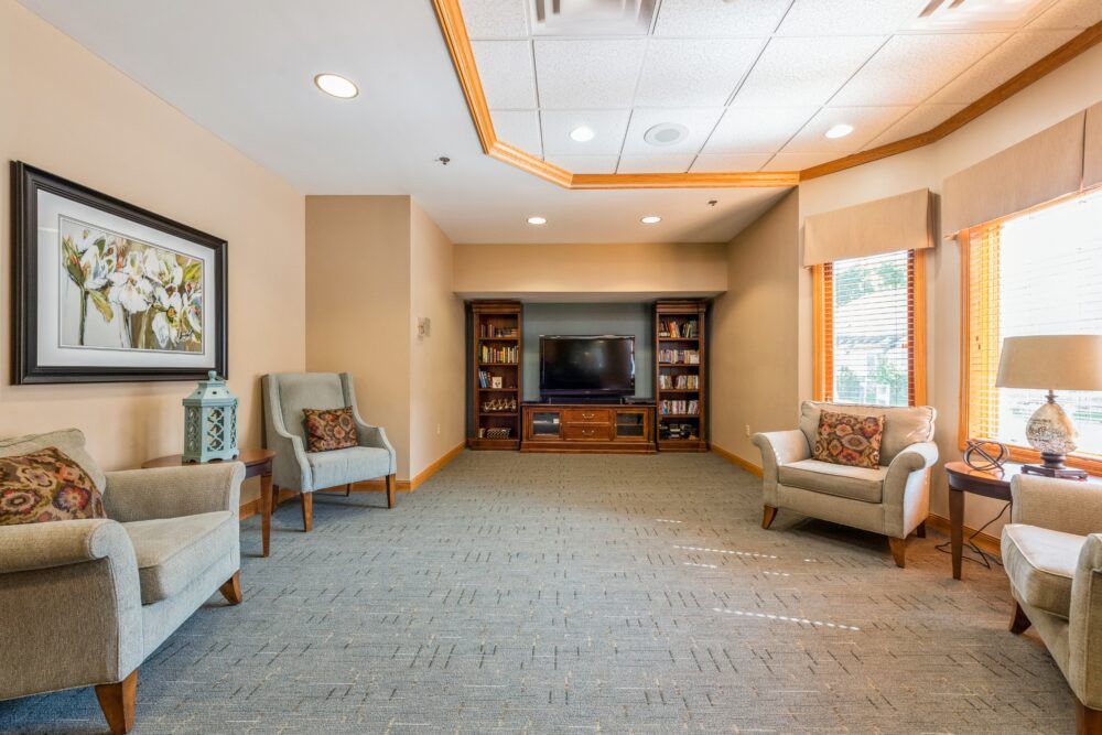 A cozy living room with armchairs, a television, and bookshelves.