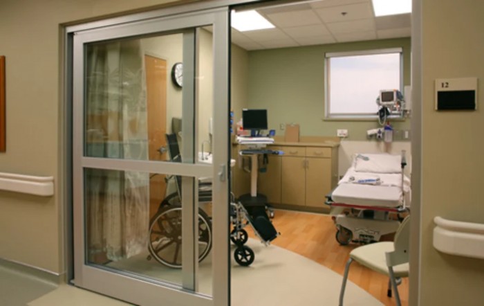 A hospital room equipped with a bed, wheelchair, and medical devices.