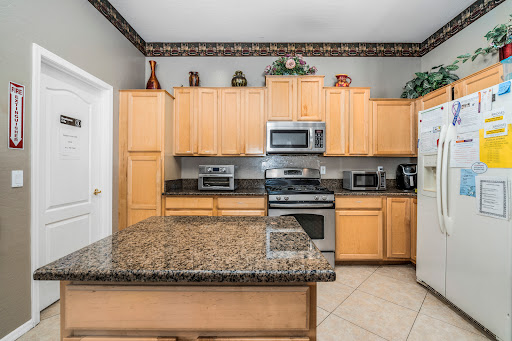 A modern kitchen featuring wooden cabinets, granite countertops, and stainless steel appliances.