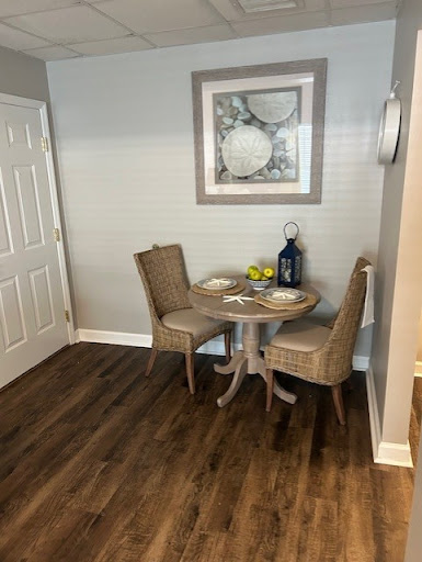 A cozy dining area featuring a small round table with two chairs, adorned with simple decor and artwork on the wall.