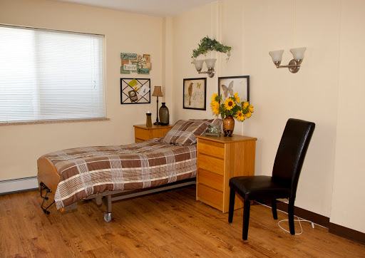 A cozy bedroom featuring a plaid bedspread, wooden furniture, and cheerful floral decor.