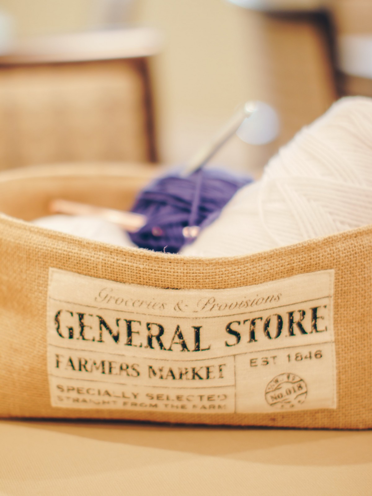 A rustic basket labeled 'General Store' filled with yarn and knitting supplies.