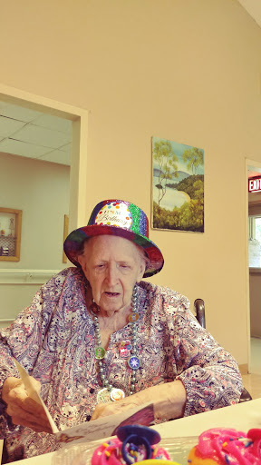 An elderly woman wearing a colorful hat, enjoying her time indoors.
