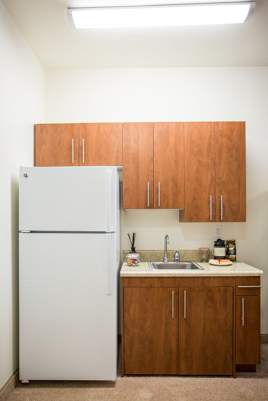 A compact kitchen with wooden cabinets, a white refrigerator, and a small sink area.