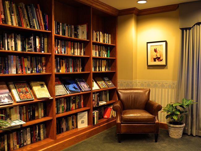 A cozy reading corner with a leather armchair and a bookshelf filled with books.