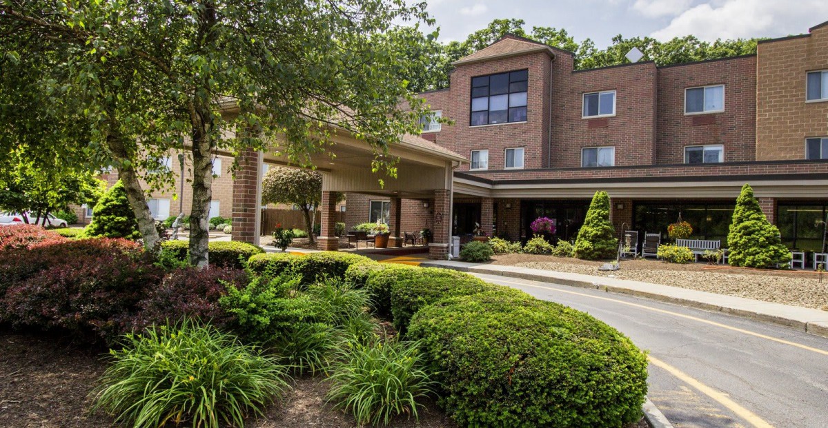 A hotel entrance surrounded by lush greenery and landscaped gardens.