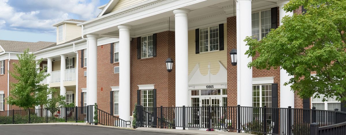 The image shows a brick building with white columns and multiple windows at the entrance.
