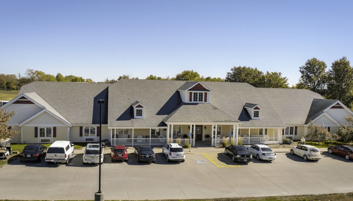 A building with a parking lot and several cars parked in front under a clear blue sky.