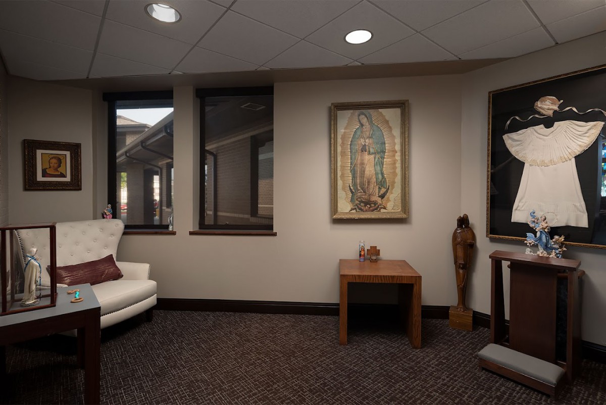 A cozy room featuring a white couch, religious artwork on the wall, and warm lighting.