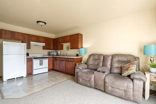 A cozy open-concept living area featuring a kitchen with wooden cabinets and a comfortable recliner sofa.