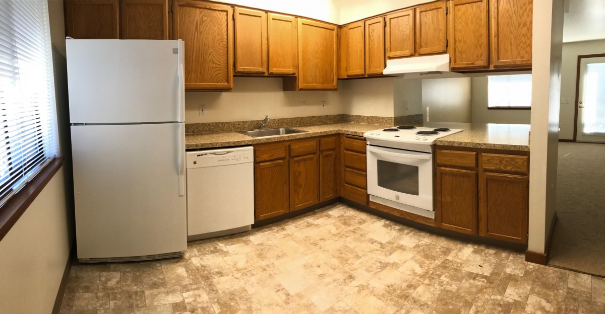 A modern kitchen with wooden cabinets and essential appliances.