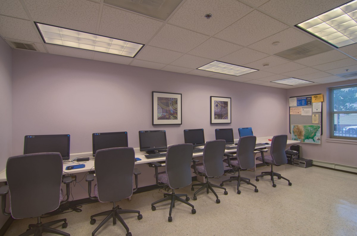 A computer lab with several workstations equipped with computers and office chairs.