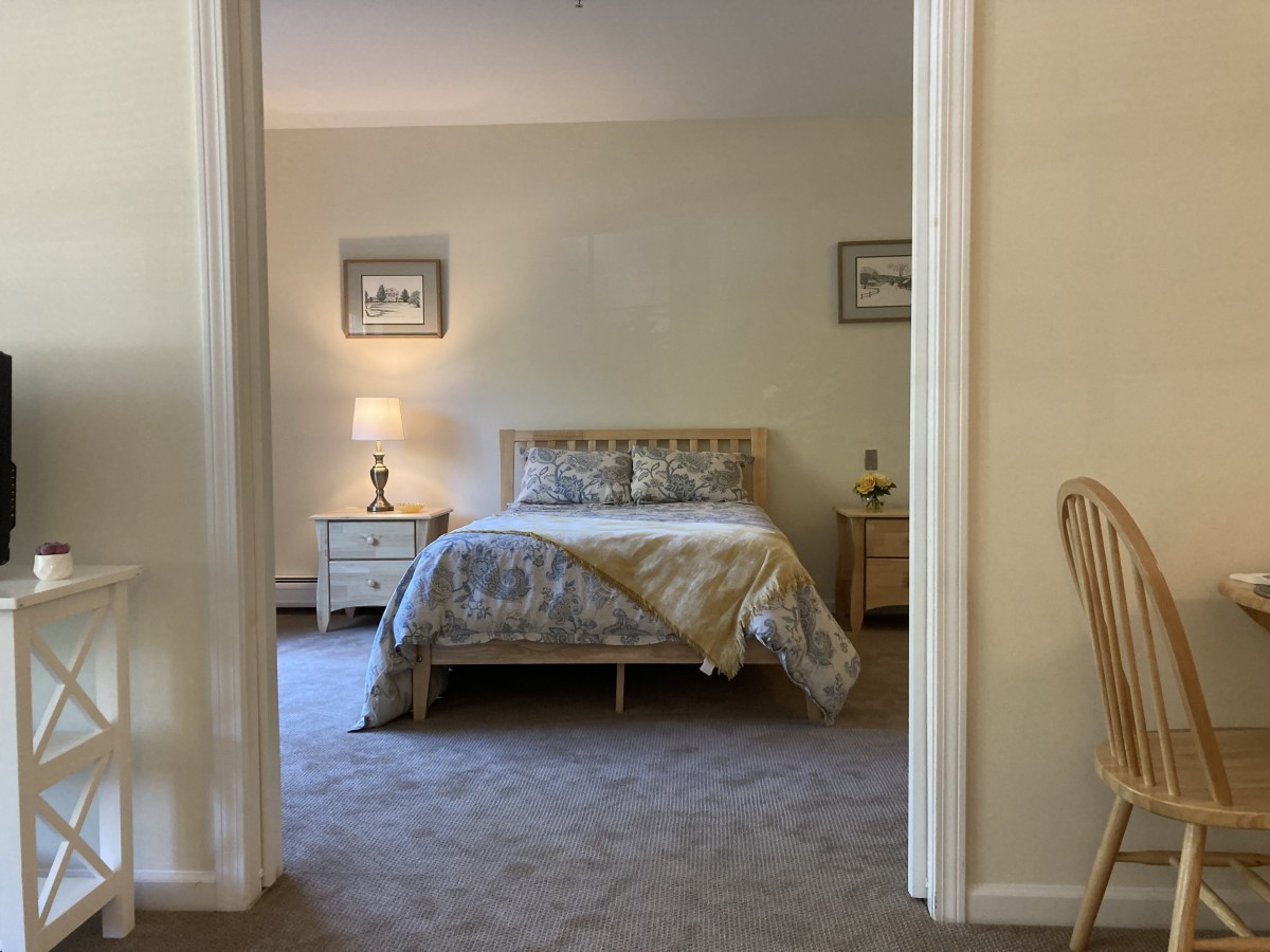 A cozy bedroom with a neatly made bed, side tables, and lamps.