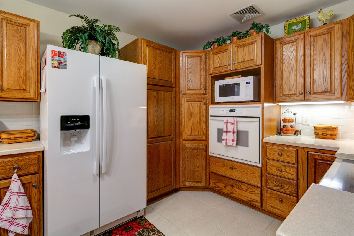 A cozy kitchen with wooden cabinets, a white refrigerator, and built-in appliances.