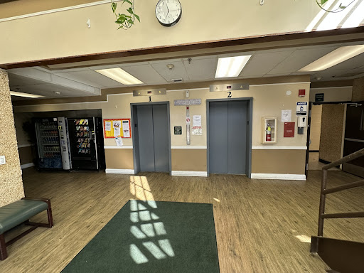 A spacious lobby featuring elevators, a clock, and a vending machine.