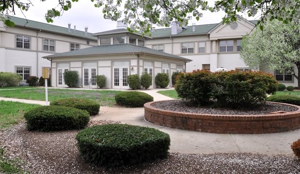 A landscaped garden area in front of a large building with green roofs and plenty of windows.