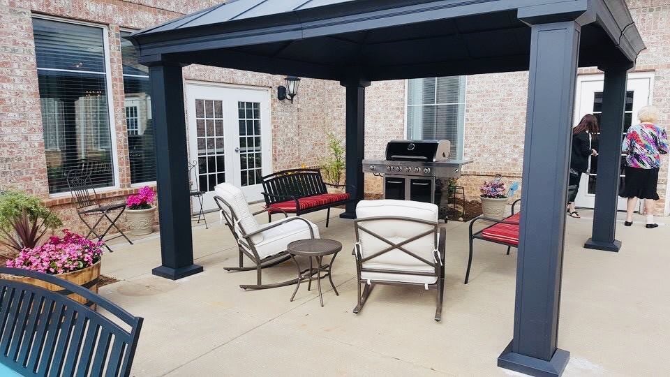 A cozy patio setup with a pergola, outdoor furniture, and a grill.