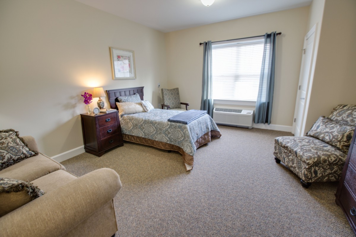 A cozy bedroom with a single bed, large window, and comfortable seating area.