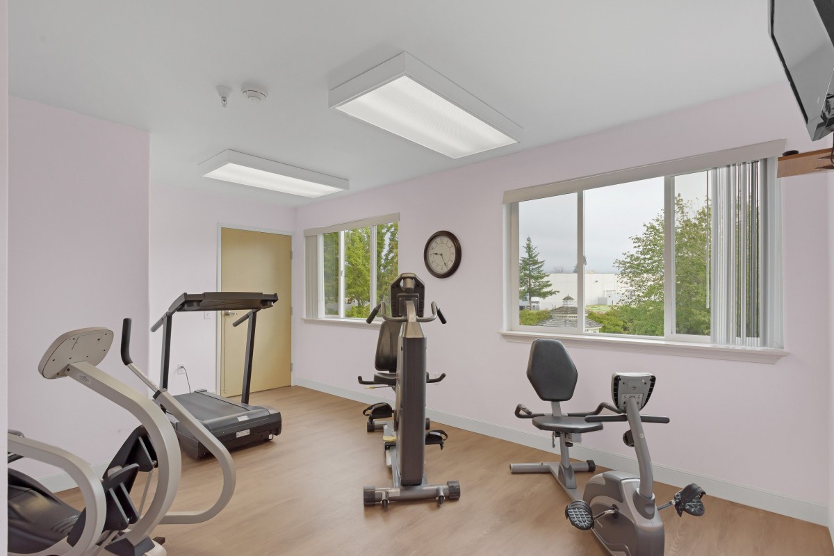 A small indoor gym with exercise equipment and windows.