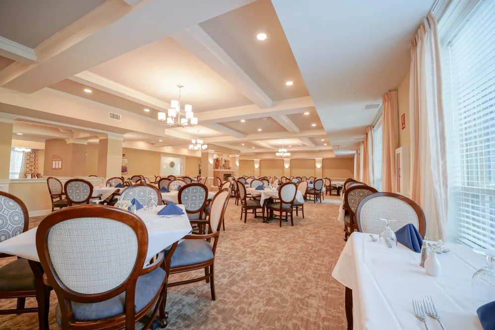 Elegant dining room with neatly arranged tables and chairs, highlighted by soft lighting.