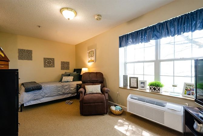 A cozy bedroom with a bed, armchair, and large window.