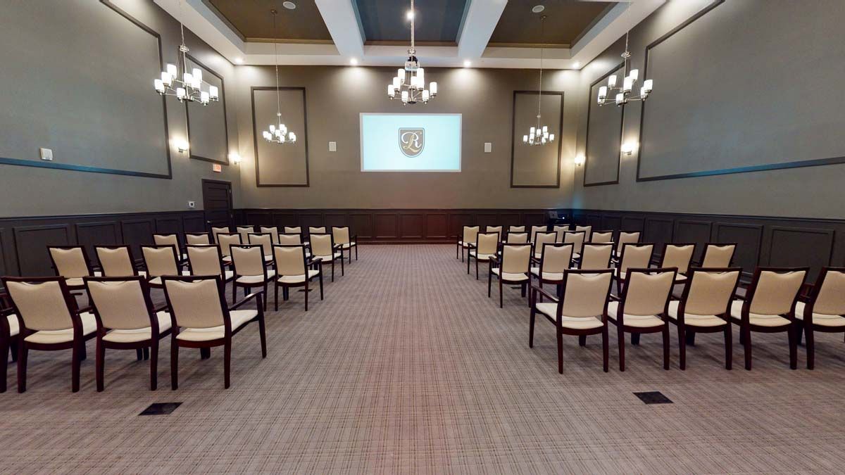 A well-arranged conference room with rows of chairs facing a projector screen.
