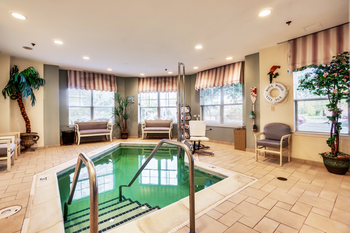 A cozy indoor therapy pool with seating and natural light.