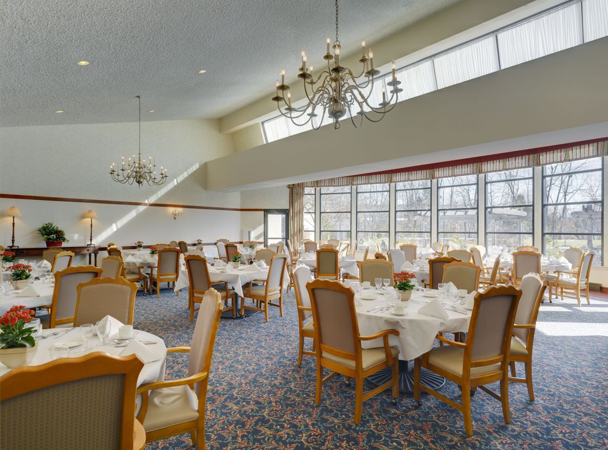 An elegant dining room with neatly arranged tables and chandeliers.
