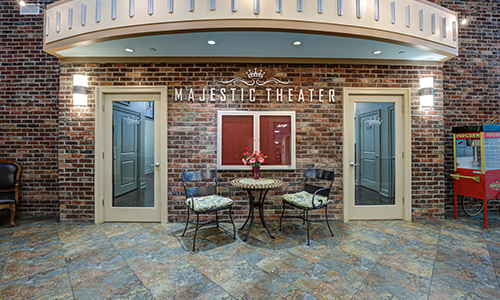 An interior view of the Majestic Theater entrance, featuring a brick wall and a seating area with a small table and two chairs.