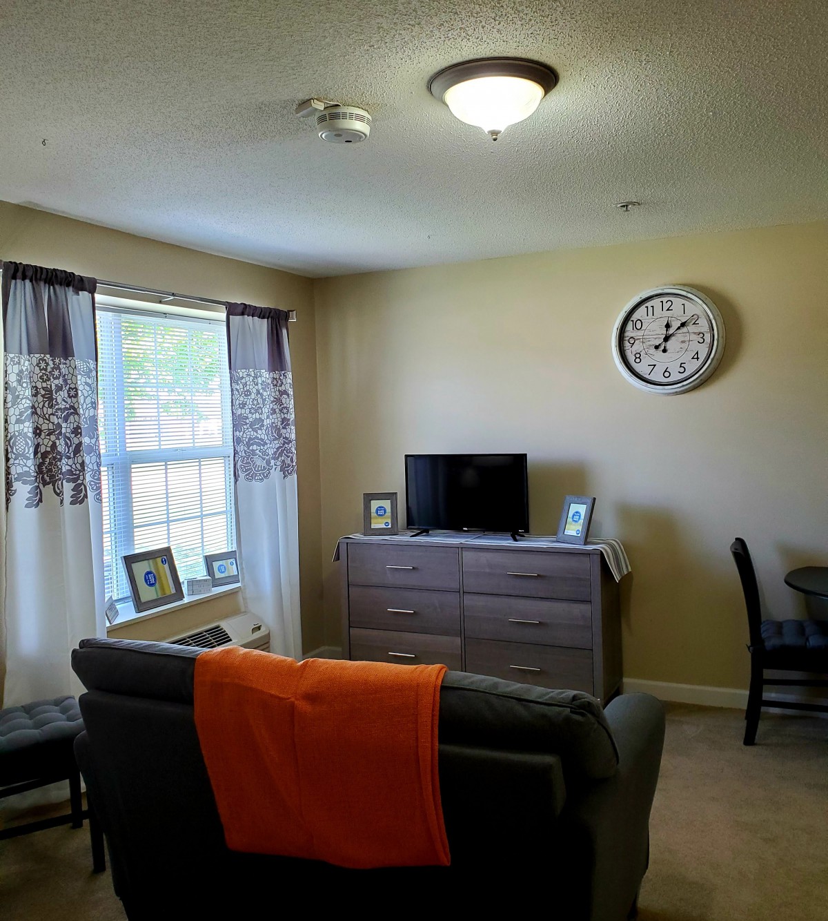 A cozy living room with a sofa, television, and wall clock.