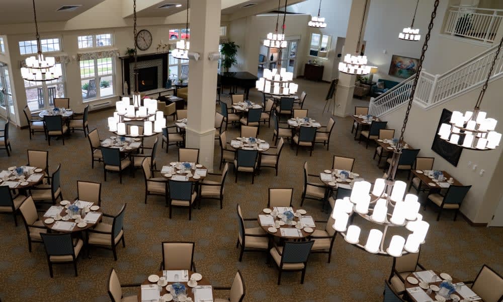 An elegant dining area with neatly arranged tables, chairs, and chandeliers.