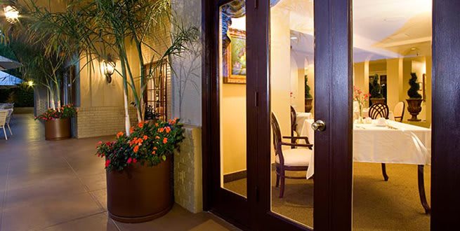 A cozy interior space with elegant decor, featuring a glass door and a large potted plant.
