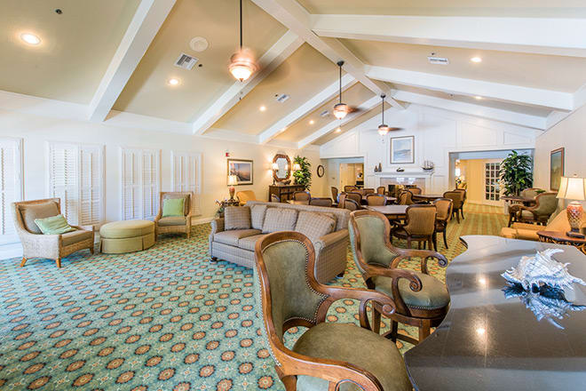 A spacious and elegantly furnished living room featuring comfortable seating, decorative lighting, and exposed ceiling beams.