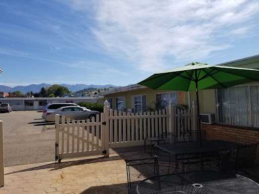 A cozy outdoor seating area with a green umbrella and a view of the mountains.