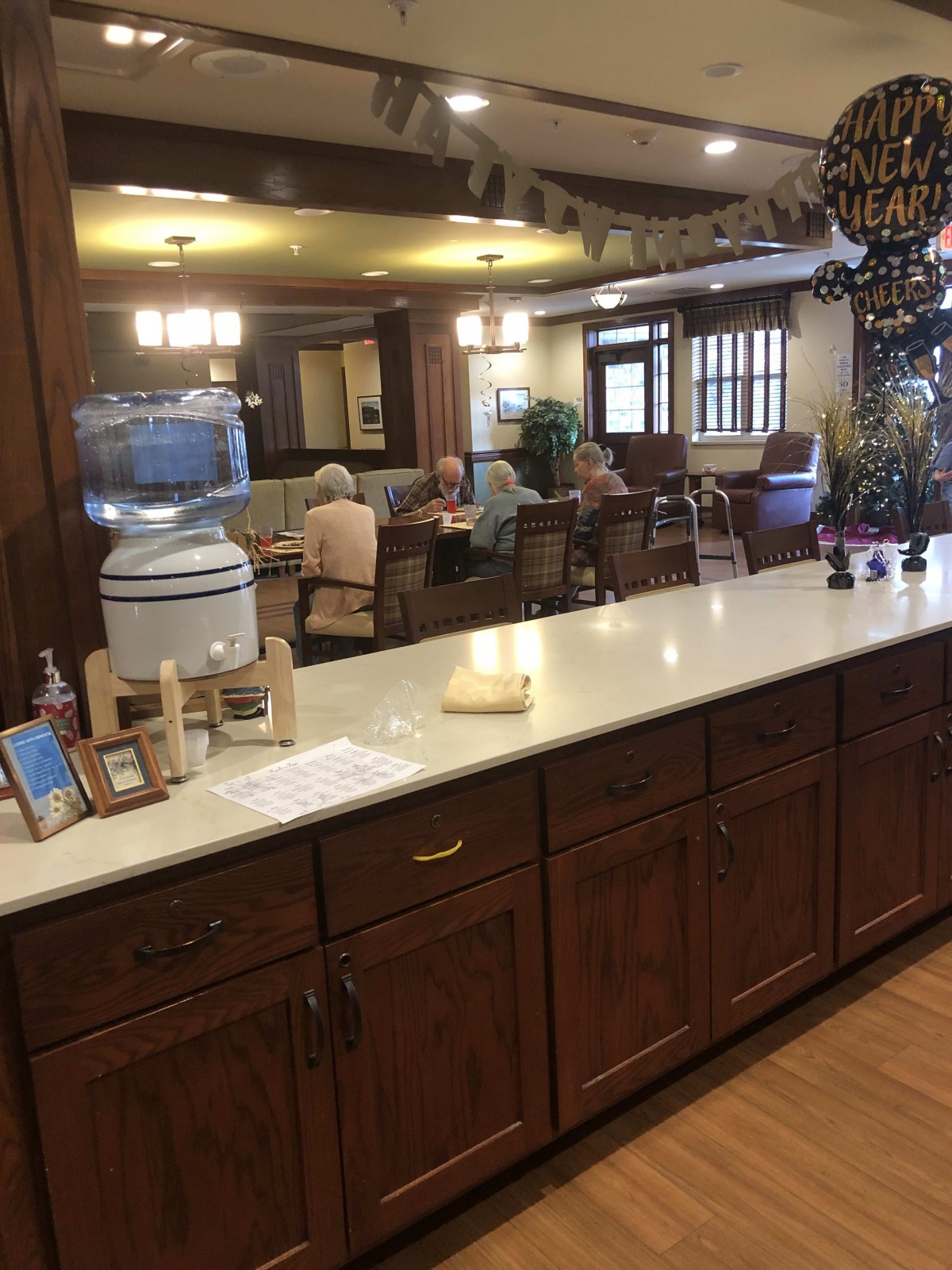 A communal dining or seating area with a countertop and elderly individuals gathered in the background.