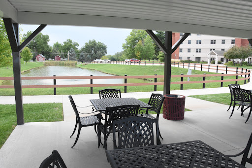 A serene outdoor patio with tables and chairs overlooking a grassy area and pond.