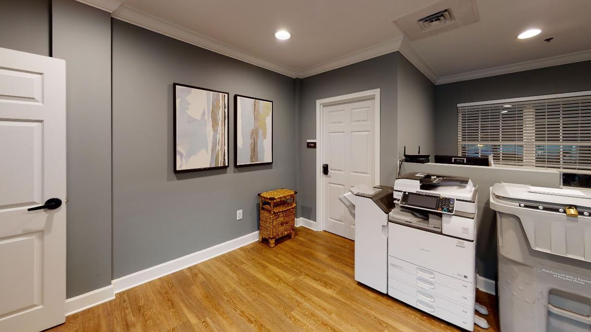A modern office space with a printer and abstract artwork on gray walls.