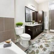 A modern bathroom with a sleek design, featuring a toilet, sink, large mirror, and shower area.