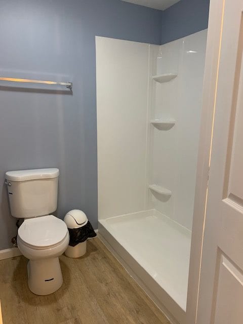 A modern bathroom featuring a toilet and shower area with light blue walls.