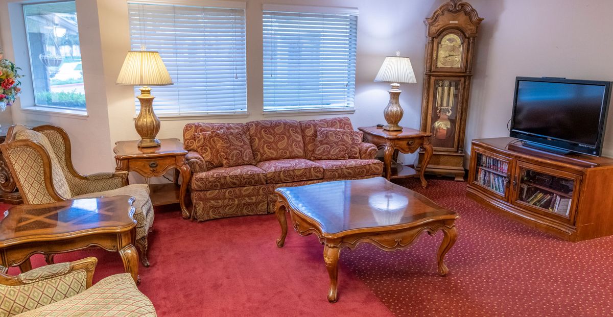 A traditional living room with a patterned sofa, wooden coffee table, and a grandfather clock.