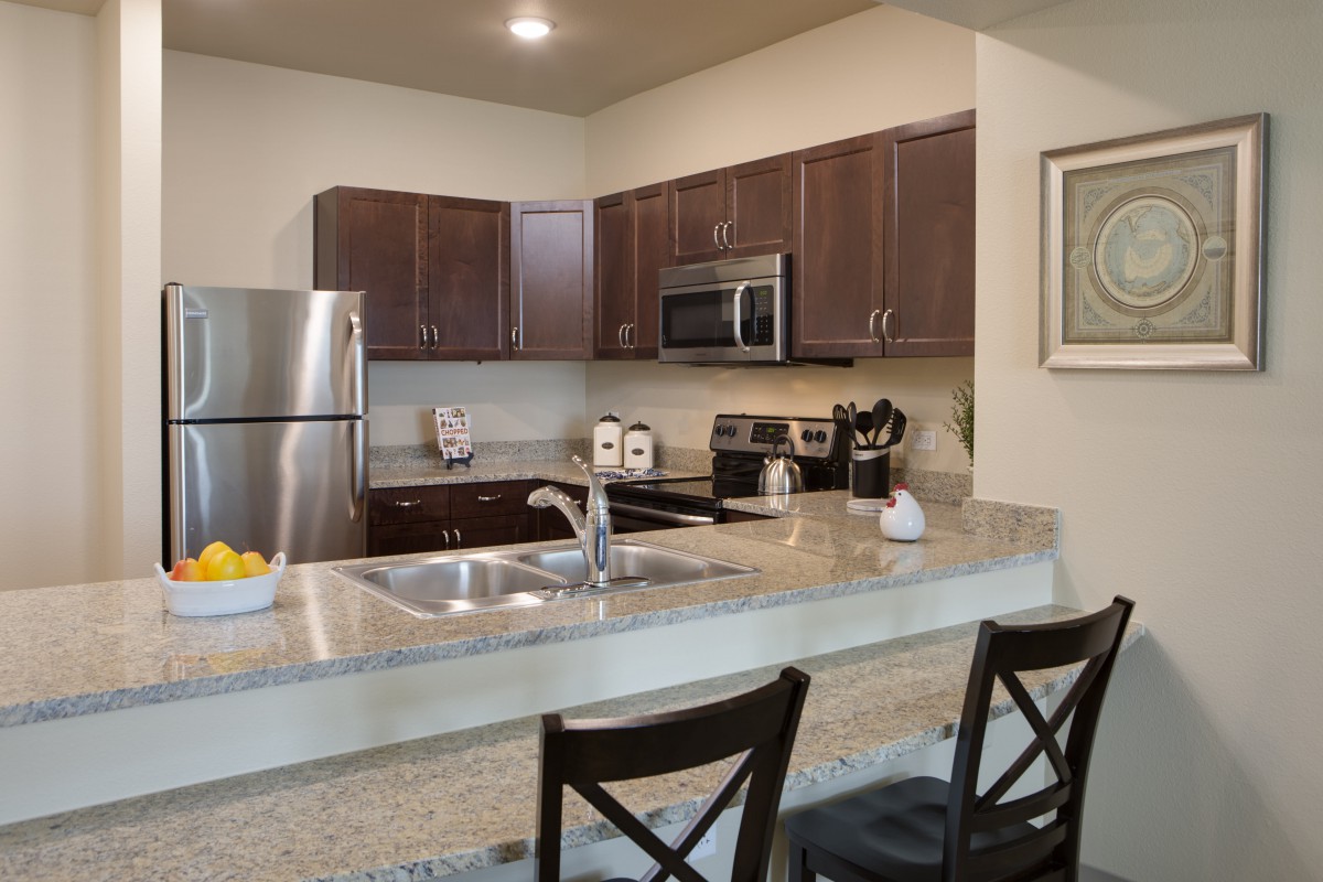 A modern kitchen with stainless steel appliances and a spacious countertop with seating.