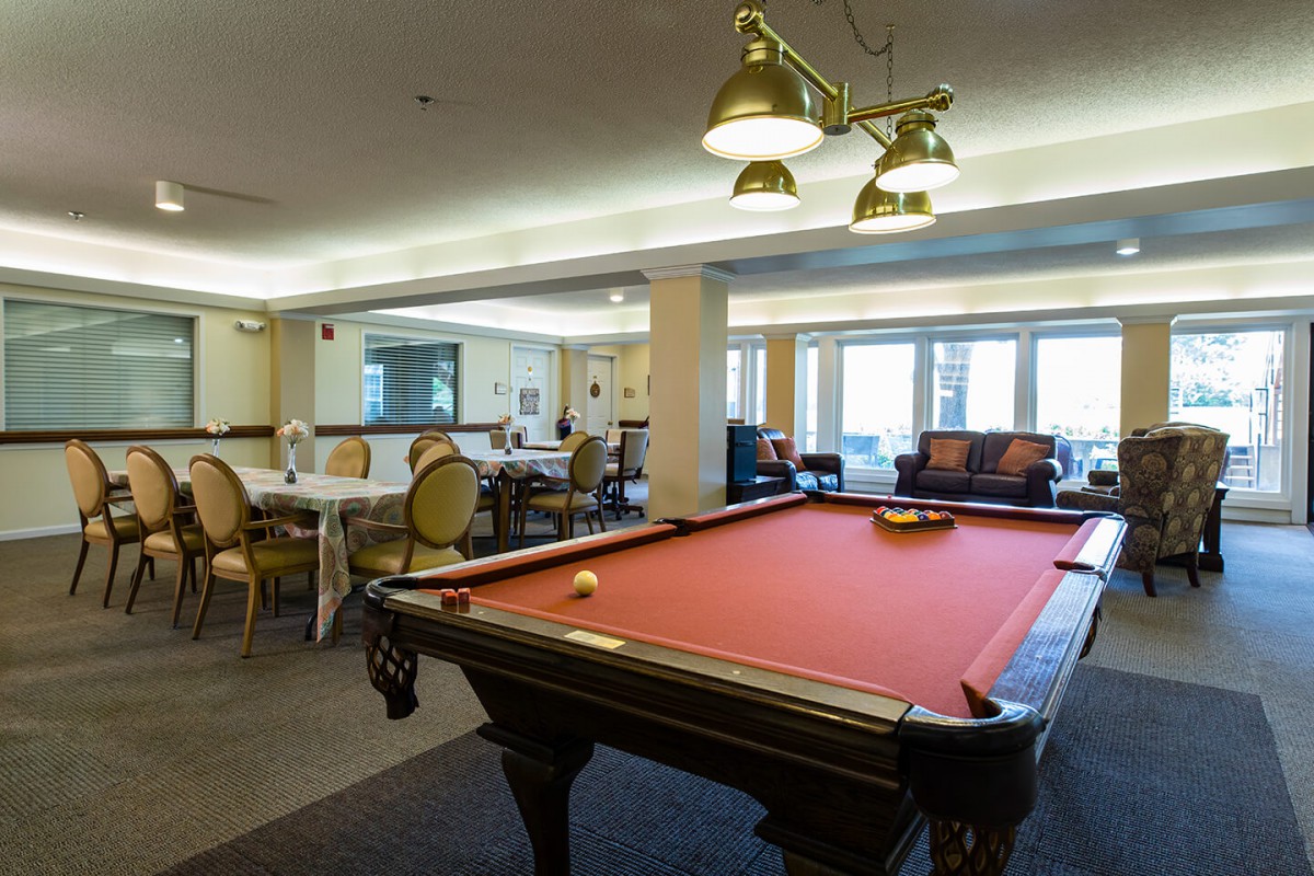 A cozy recreation room featuring a pool table with red felt and elegant lighting.