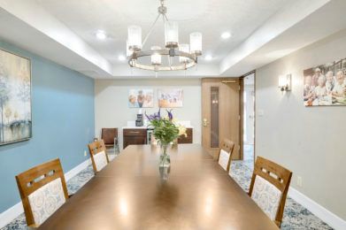 A well-decorated dining room with a large table and elegant chairs under a chandelier.