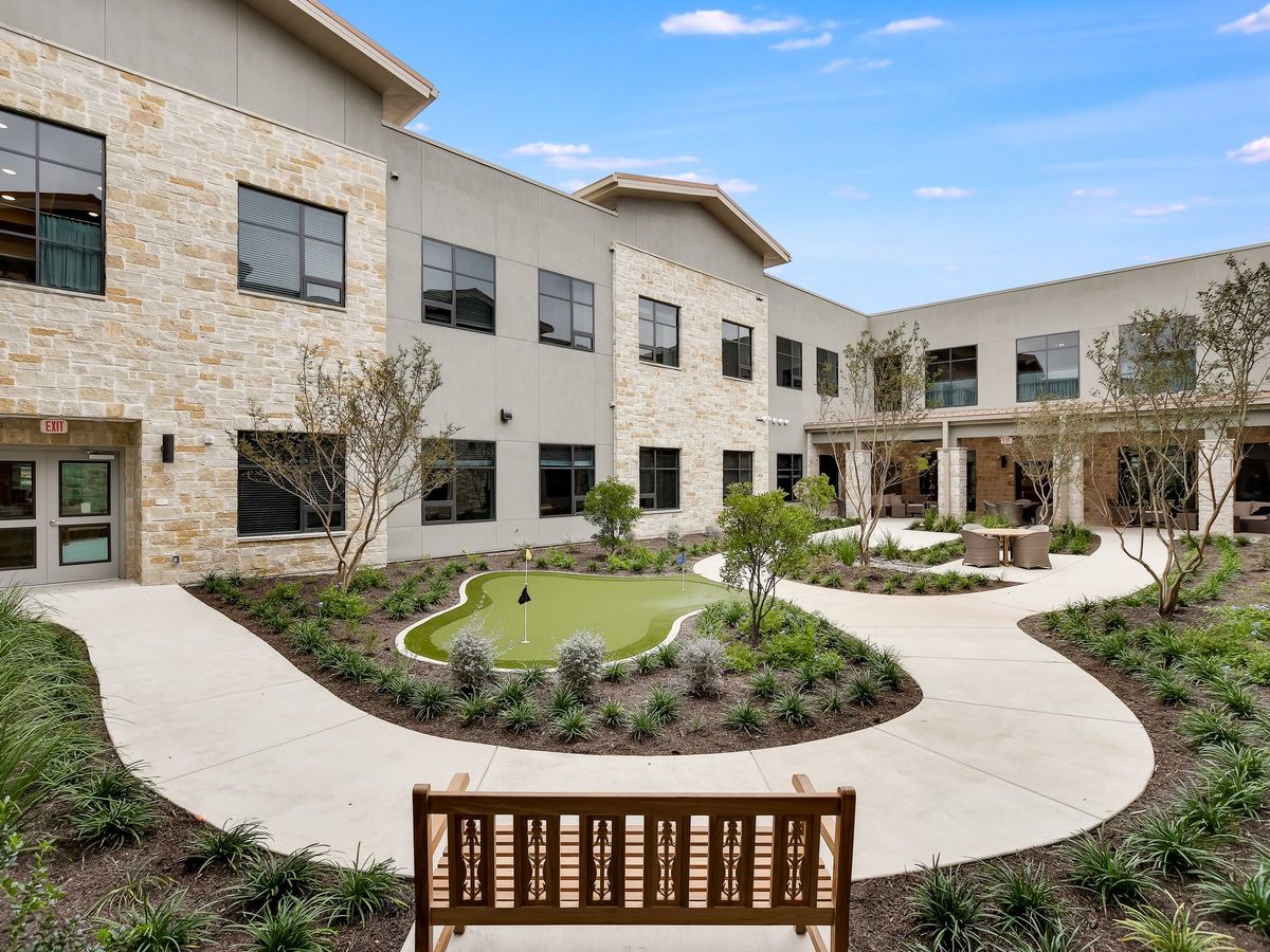 A modern building with a landscaped courtyard, featuring benches and pathways.