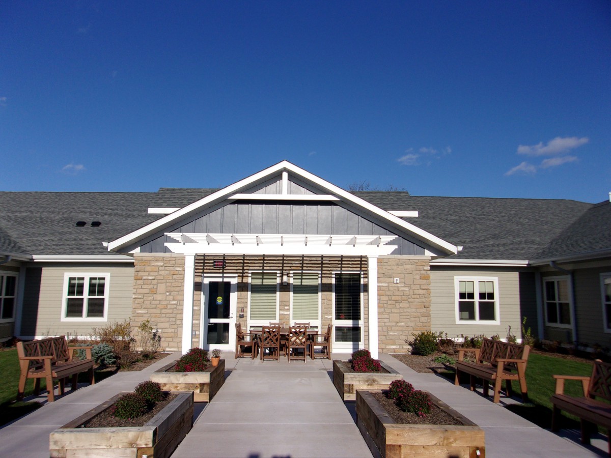 A modern residential building with a landscaped entrance and clear blue sky.